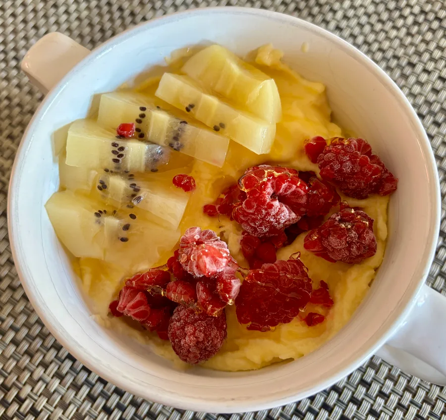 Mango-ijs ontbijt van rauwe melk met kokos, kiwi en frambozen