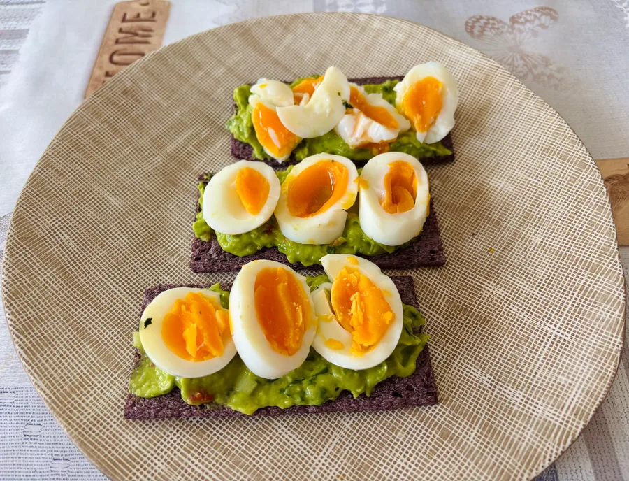 Zwarte rijstcracker met guacamole en ei