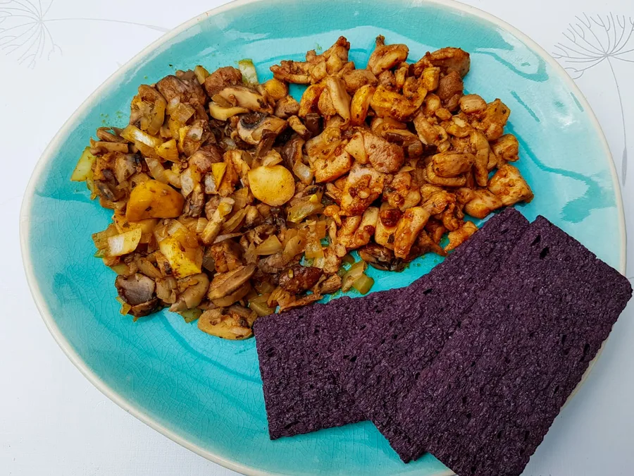 Zwarte rijstcrackers met kipfilet en paddenstoelen